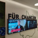 Acrylbeschriftung über einem Bildschirm als Wandgestaltung