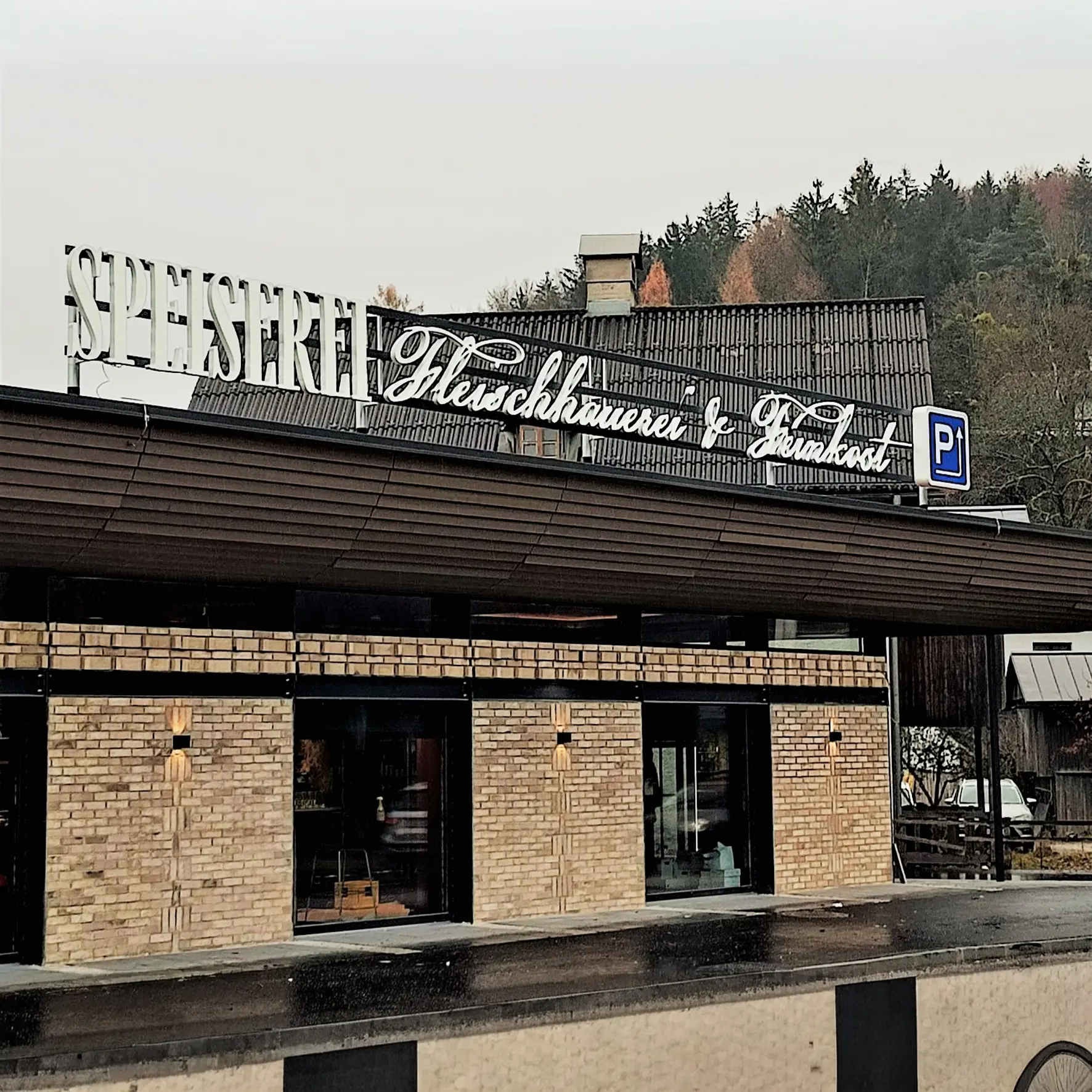 Beleuchteter Unternehmensschriftzug mit Frontleuchtern über dem Eingang