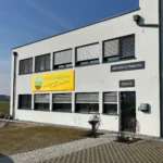 Fassadenschild mit Firmenlogo und Schriftzug an moderner Gebäudeaußenwand