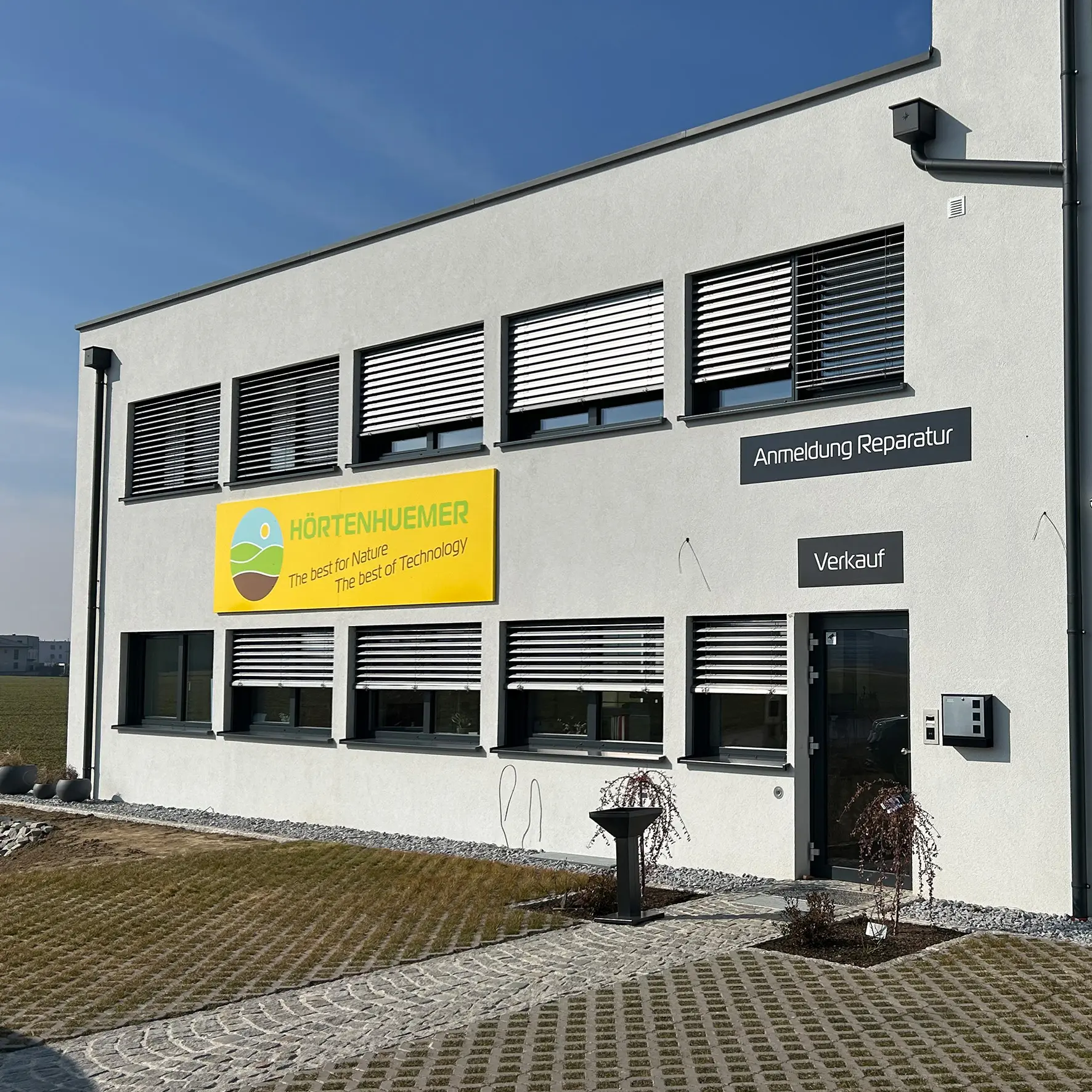 Fassadenschild mit Firmenlogo und Schriftzug an moderner Gebäudeaußenwand