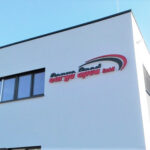 Beleuchteter Markenname mit Frontleuchtern an einer Fassade