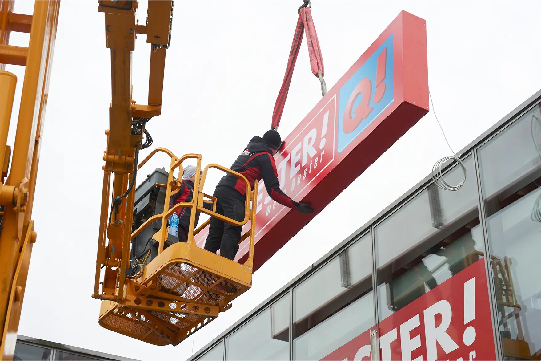 Handwerker montieren eine Werbeanlage an der Fassade