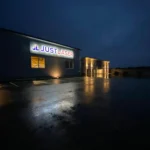 Frontleuchter an Firmenfassade – beleuchteter Unternehmensschriftzug bei Nacht