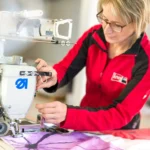 Mitarbeiterin beim Nähen eines Flachkeders an einen Textildruck